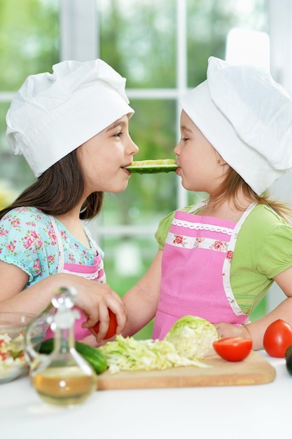 Cute girls with cucumber in kitchen