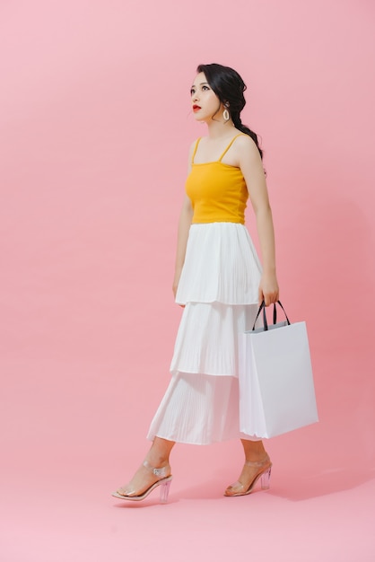 Cute glamour young asian lady posing with white bags of purchases