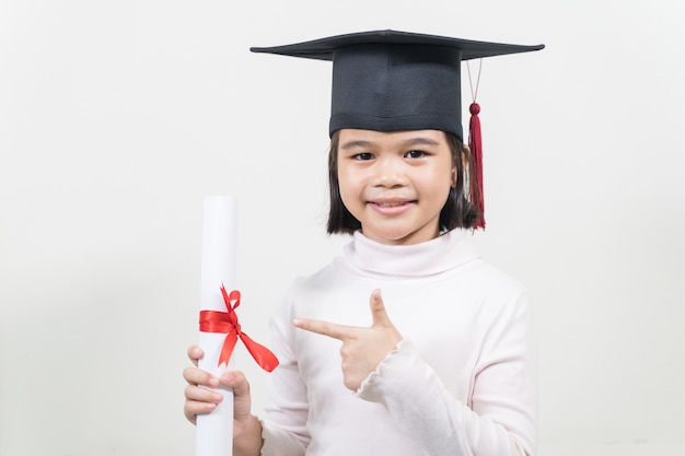 Фото Милый счастливый азиатский школьный выпускник с выпускной шляпой и дипломом, изолированным на белом фоне