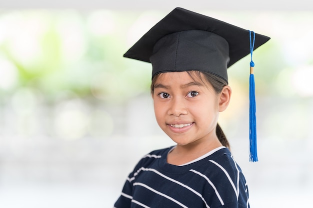 Foto carino felice ragazzo asiatico diplomato con cappello di laurea e un diploma isolato su sfondo bianco