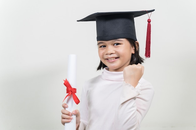 Cute happy Asian school kid graduate with graduation hat and a diploma isolated on white background