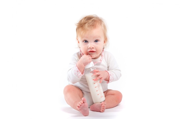 Фото Милый счастливый ребенок в белой рубашке держит бутылку