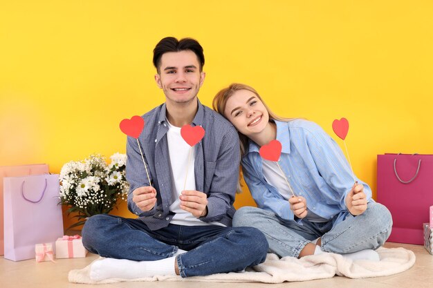 Cute and happy couple sitting against yellow background