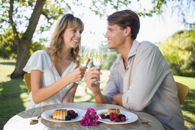 Cute happy couple sitting outside toasting with champagne with dessert