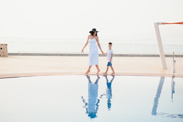 Cute happy family having fun near pool on luxury tropical resort, mother with child