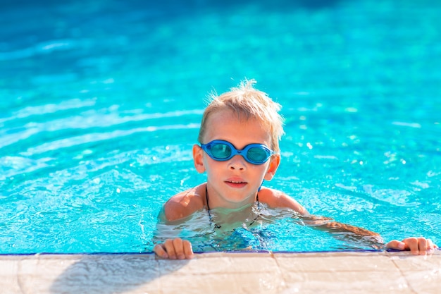 Cute happy little boy in goggles swimming and snorking in the swimming pool. Swimming for kids concept