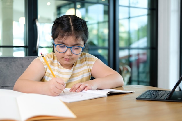 Bambine carine e felici che usano il computer portatile, studiando attraverso il sistema di e-learning online.