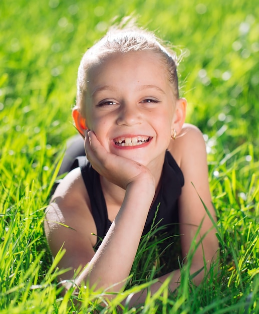Cute happy little girl lying on the grass