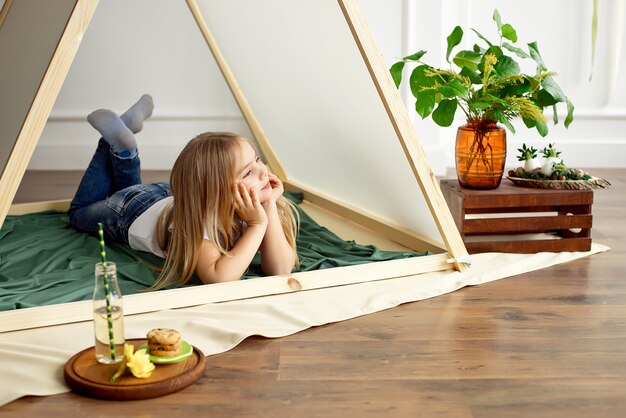 Bambina felice sveglia che posa in una tenda