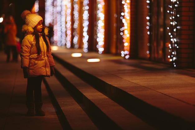 写真 かわいい幸せな少女が大都市の通りを歩く