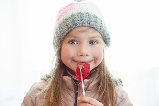 Cute happy little girl with lollipop candy with copyspace