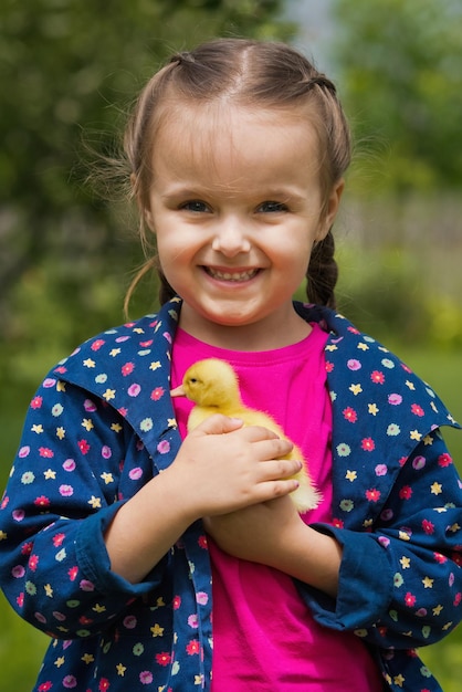 Cute happy little girl with of small duckling in the garden