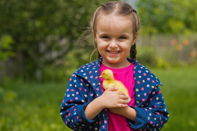 Cute happy little girl with of small duckling in the garden