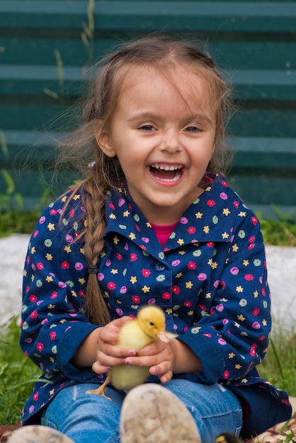 Cute happy little girl with of small ducklings in the garden