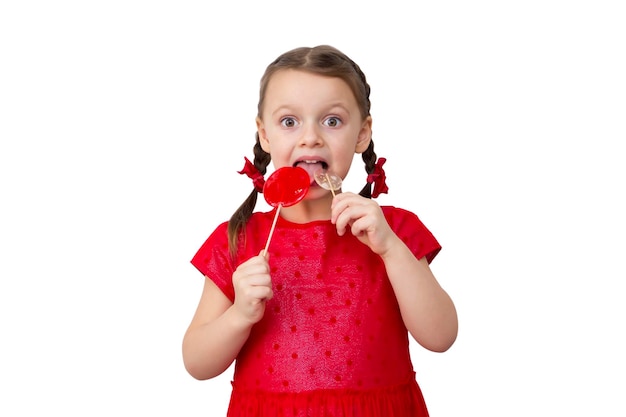 Cute happy little surprised girl with two lollipops in red dress isolated on white background