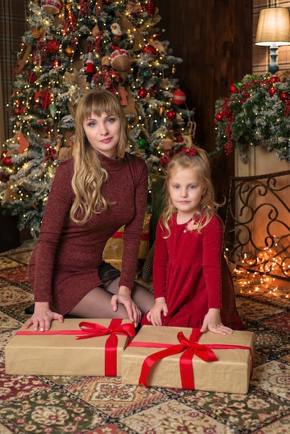 милая и счастливая мама и дочь возле елки с подарками. вместе на рождество