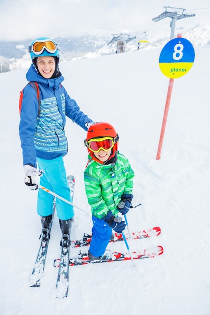 Cute happy skier boy with his sister in a winter ski resort.