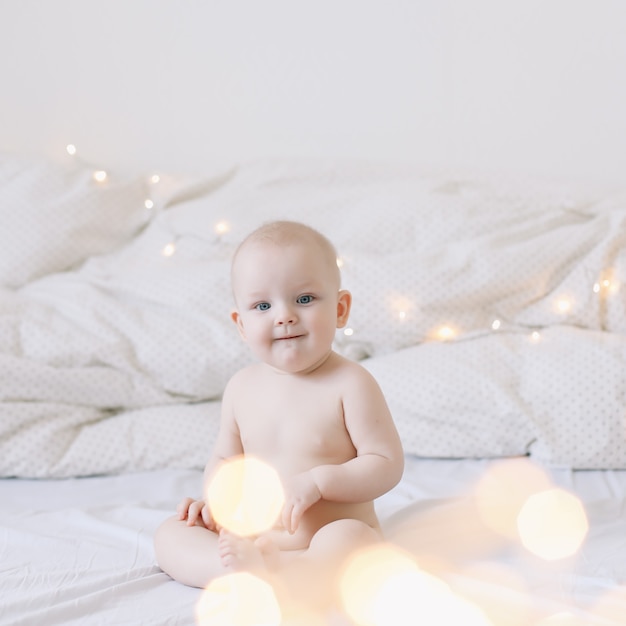 Cute happy smiling baby sits on the bed