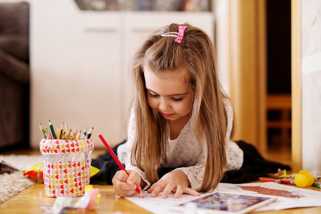 Cute happy toddler girl is playing with coloured pencils.