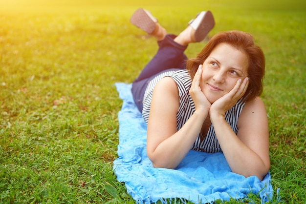 Cute happy woman lying on the green grass resting