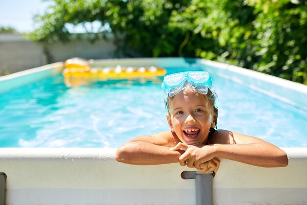 A cute happy young girl child playing in swimming pool wearing blue diving mask