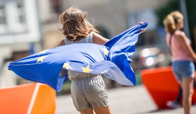 Cute happy young girl with the flag of the European Union.