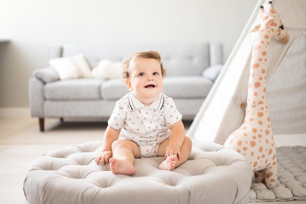 A cute healthy baby boy in a spacious bright children's room at home with a wigwam soft toys children's textiles A child is playing in the living room of the house