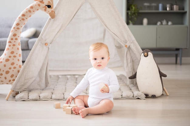 A cute healthy baby boy in a spacious bright children's room at home with a wigwam soft toys children's textiles A child is playing in the living room of the house