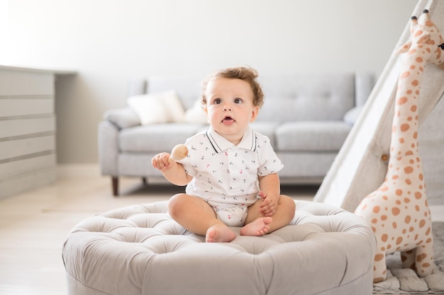 A cute healthy baby boy in a spacious bright children\'s room at\
home with a wigwam soft toys children\'s textiles a child is playing\
in the living room of the house