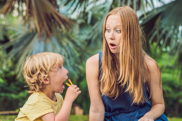 Un bambino in età prescolare in buona salute mangia patate fritte con ketchup con sua madre. bambino che mangia cibo malsano. la mamma era sconvolta.