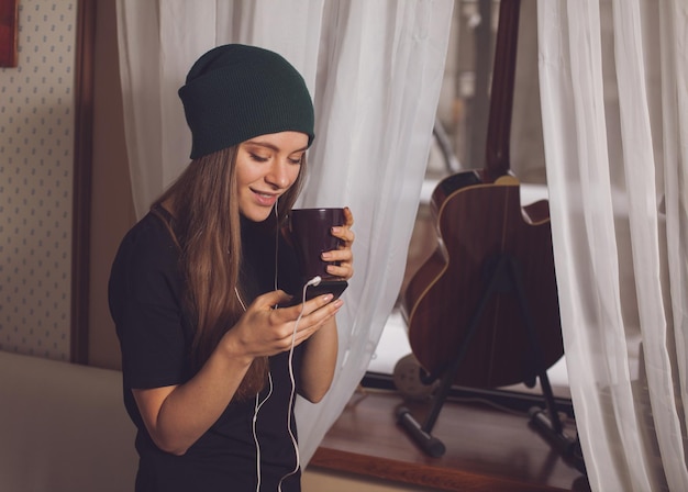 Cute hipster woman listening music near guitar