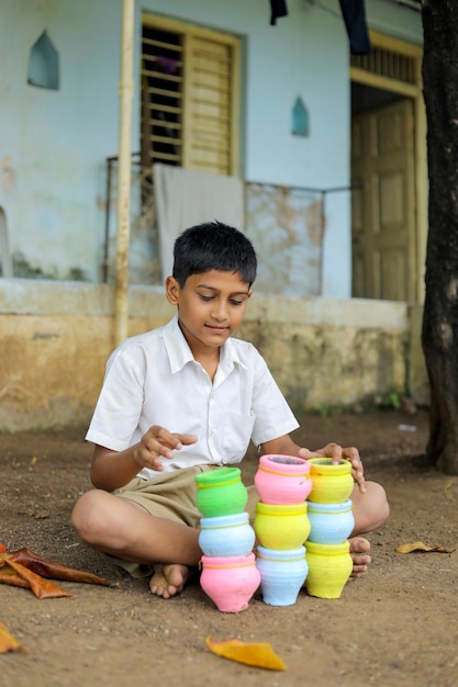 Cute indian boy playing with colourful bowls on the street