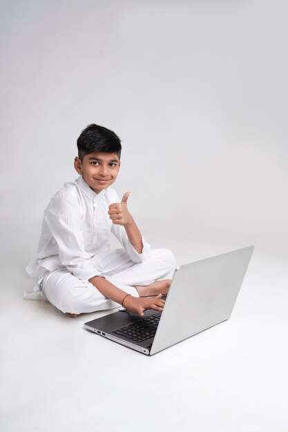 Симпатичный индийский мальчик, использующий ноутбук и показывая большие сиськи