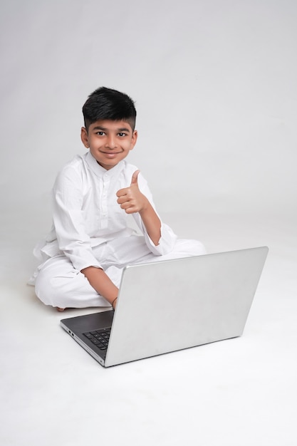 Cute indian boy using laptop and showing thumps up  