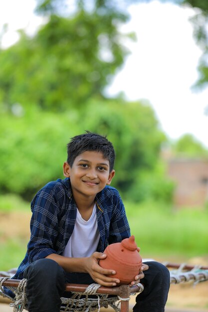 Carino bambino indiano tenendo in mano argilla salvadanaio