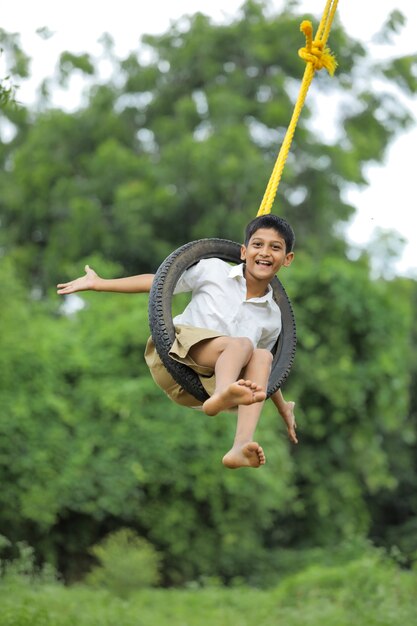 Cute Indian child sitting in a tire swing