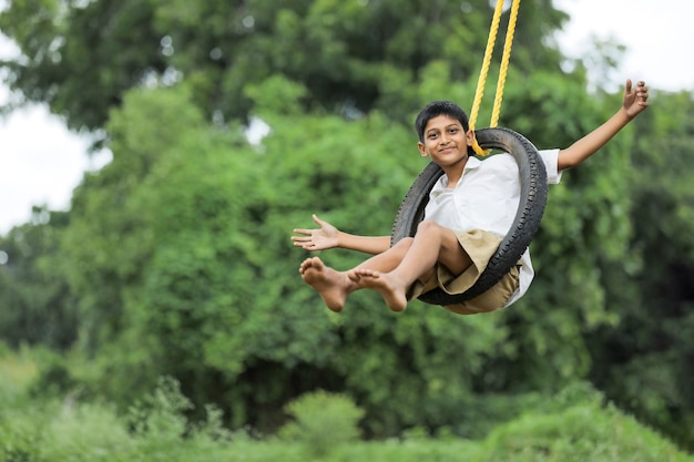 Cute Indian child sitting in a tire swing