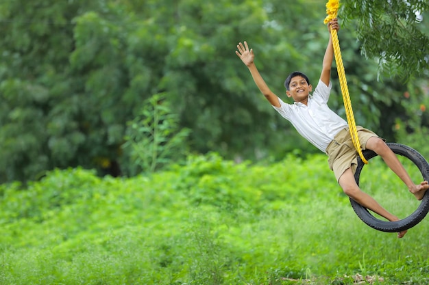 Cute Indian child sitting in a tire swing