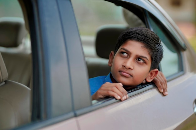 車の窓から手を振っているかわいいインドの子供。