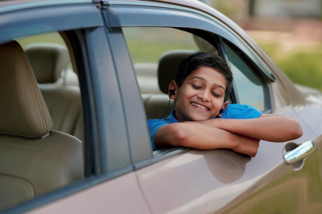 車の窓から手を振っているかわいいインドの子供。