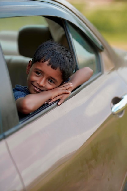 車の窓から手を振っているかわいいインドの子供。