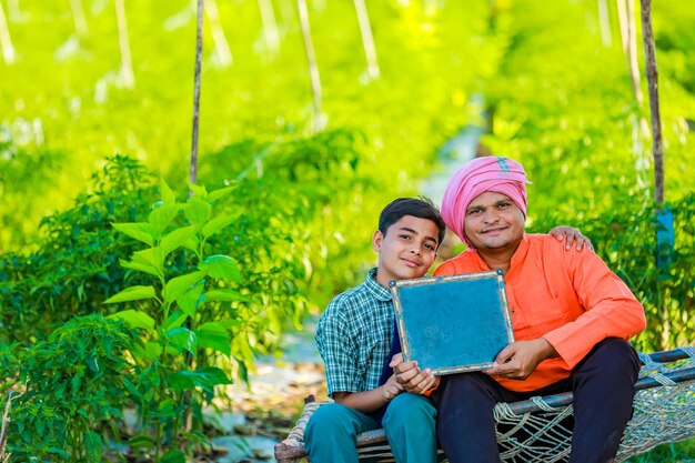 Cute indian farmer child in school uniform with his father at agriculture field