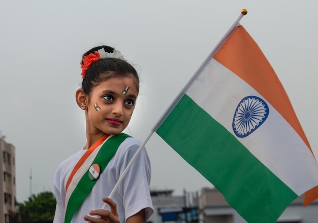 Cute indian girl kid holding indian flag celebrating indian independence day showing patriotism