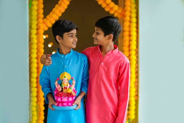 Cute Indian little boy holding goddess laxmi sclupture in hand and celebrate diwali festival.