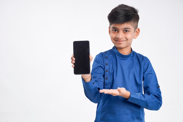 白でスマートフォンの画面を示すかわいいインドの小さな男の子