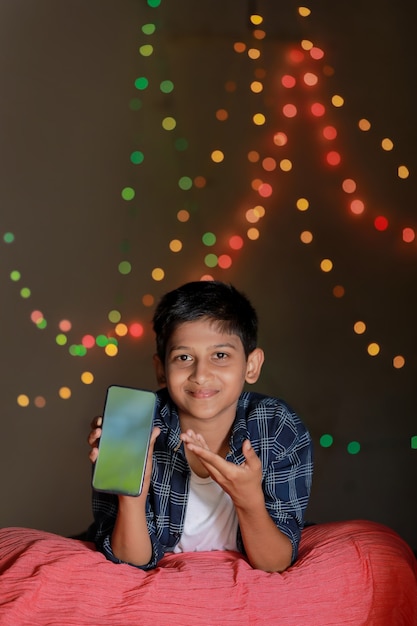 Cute indian little child showing smart phone screen and giving expression