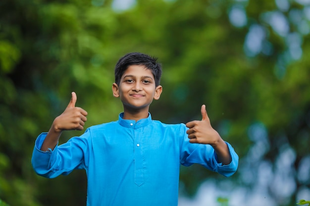 Cute indian little child in traditional wear and standing at agriculture field