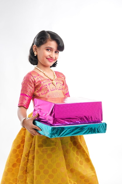 Cute indian little girl Child with gifts boxes in traditional cloths standing isolated over white background