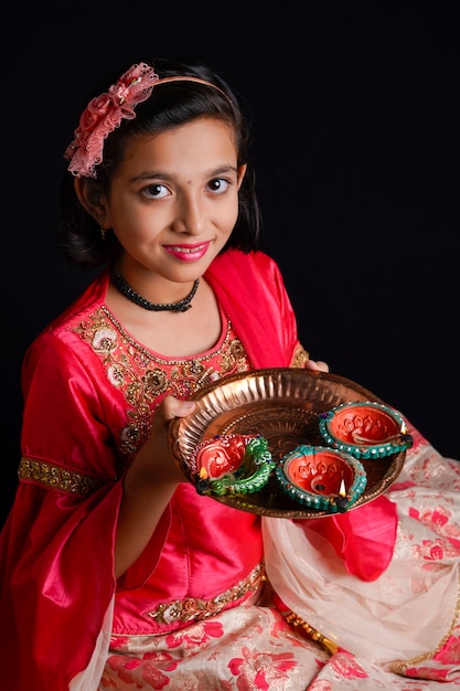Carina bambina indiana che tiene diya o lampade a olio per la celebrazione del diwali.