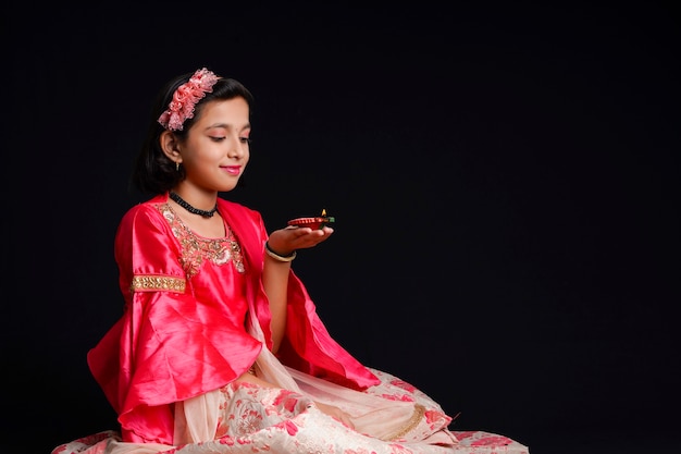 Cute Indian little girl holding diya or oil lamps for Diwali Celebration.